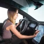 e-Wave driver using digital GPS navigation inside electric executive car for Alconbury Weald airport transfer