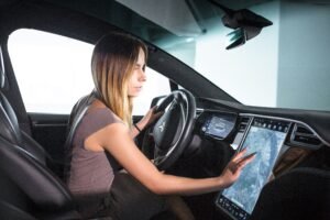e-Wave driver using digital GPS navigation inside electric executive car for Alconbury Weald airport transfer